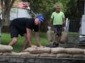 Mount Ousley Public School parents Joel Scott and Luke Smith placing sandbags to help protect the school during predicted wet weather this weekend. Picture by Robert Peet